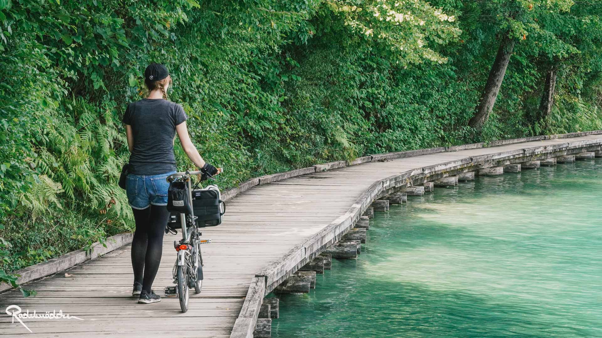 Frau mit Faltrad am See auf einem Steg