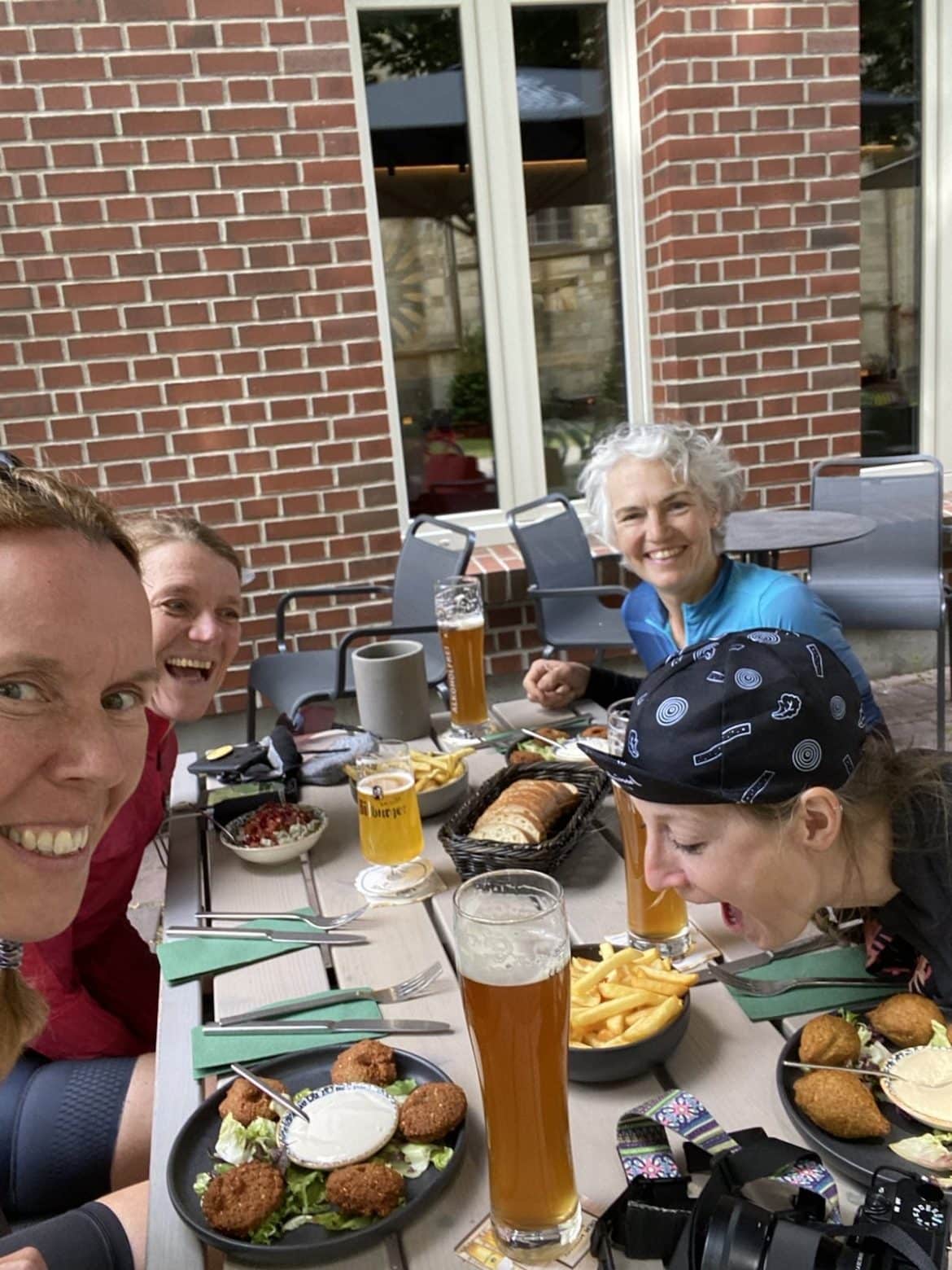 vier Frauen sitzen draußen an einem Tisch mit Essen und lachen