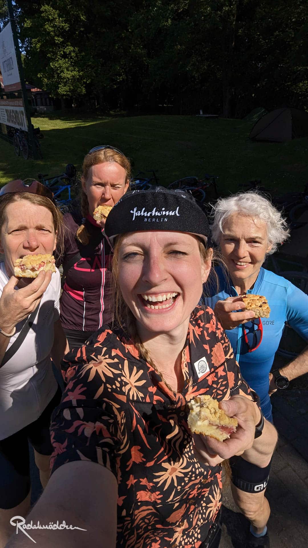 Vier Frauen lachen in die Kamera mit Kuchen in der Hand