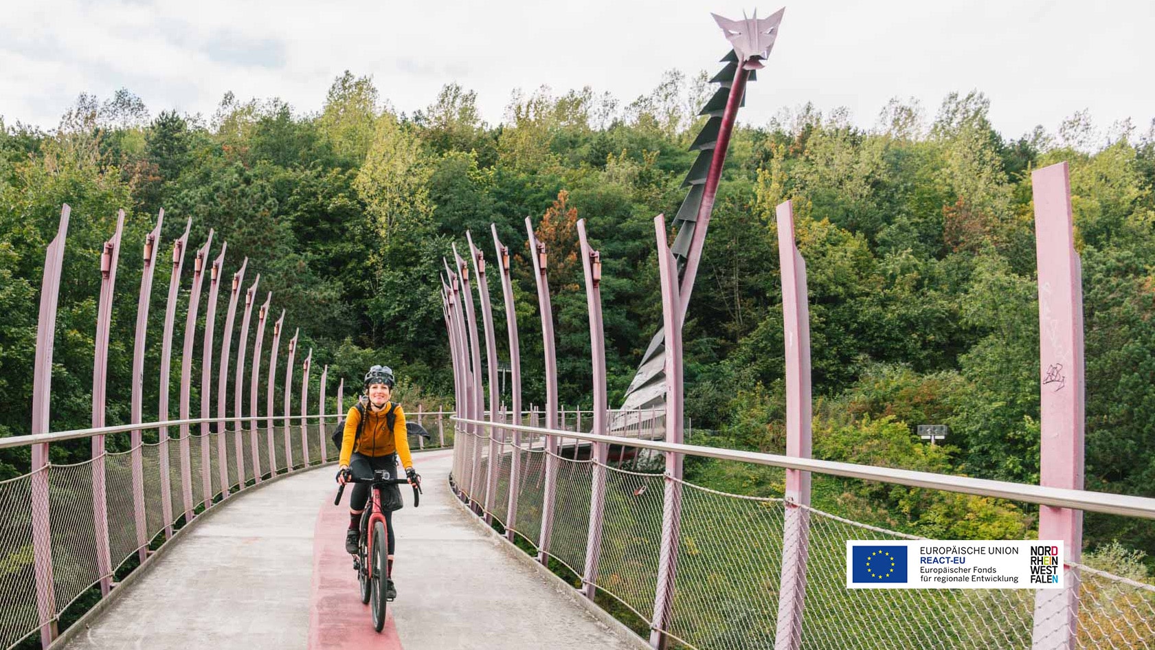 Frau auf Fahrrad auf einer Brücke mit Drachenkopf