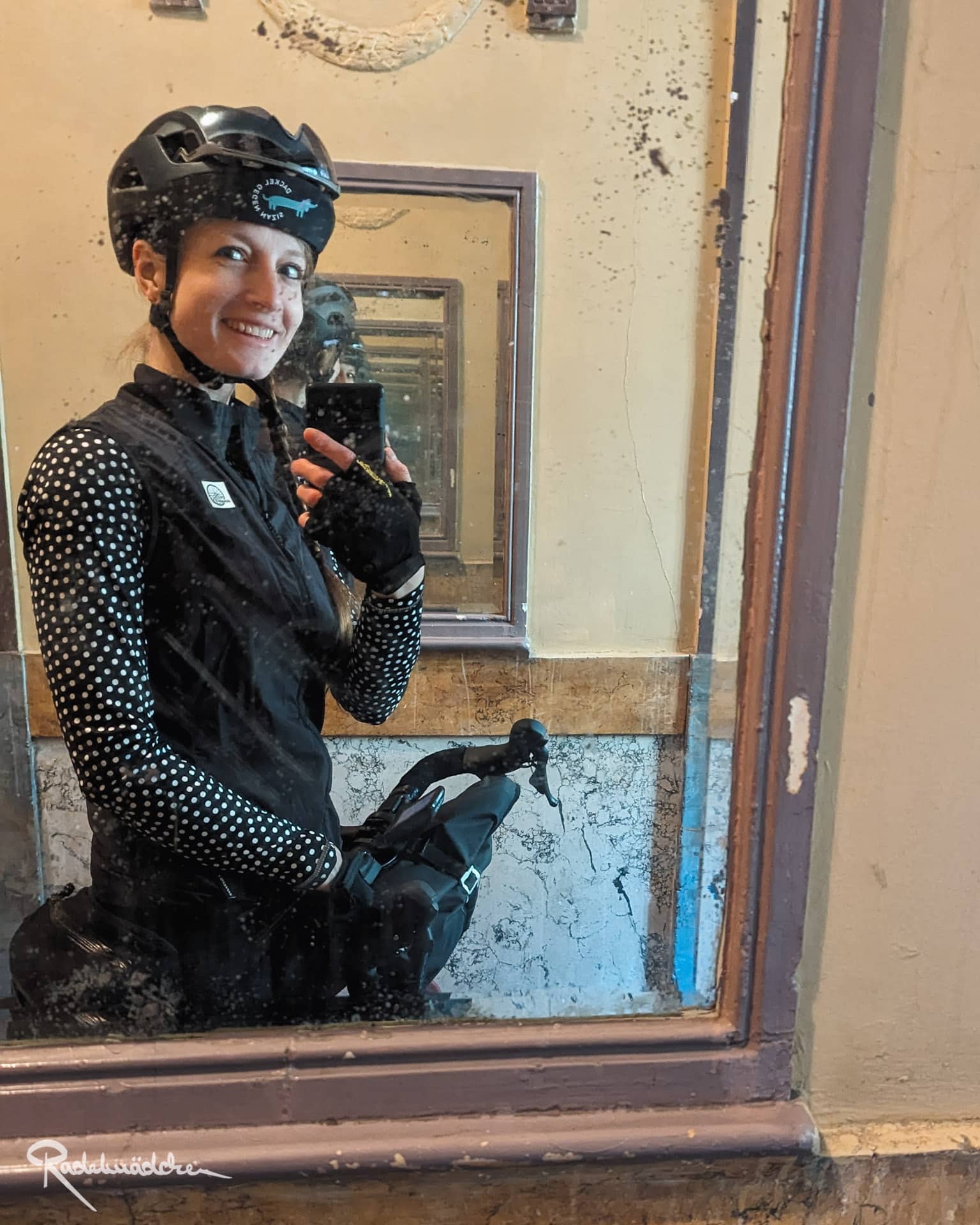 Frau mit Fahrradkleidung und Helm vor einem Spiegel