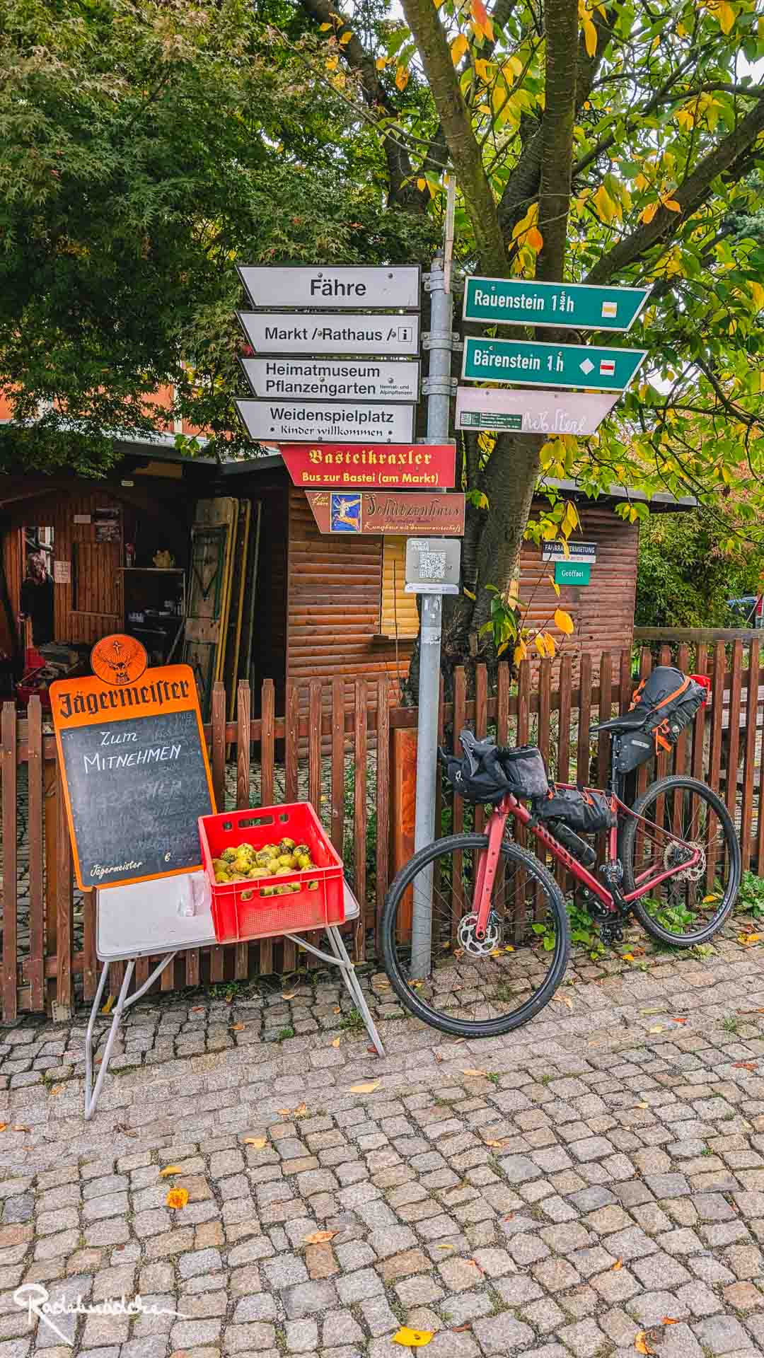 Schilder und Fahrrad an einem Zaun