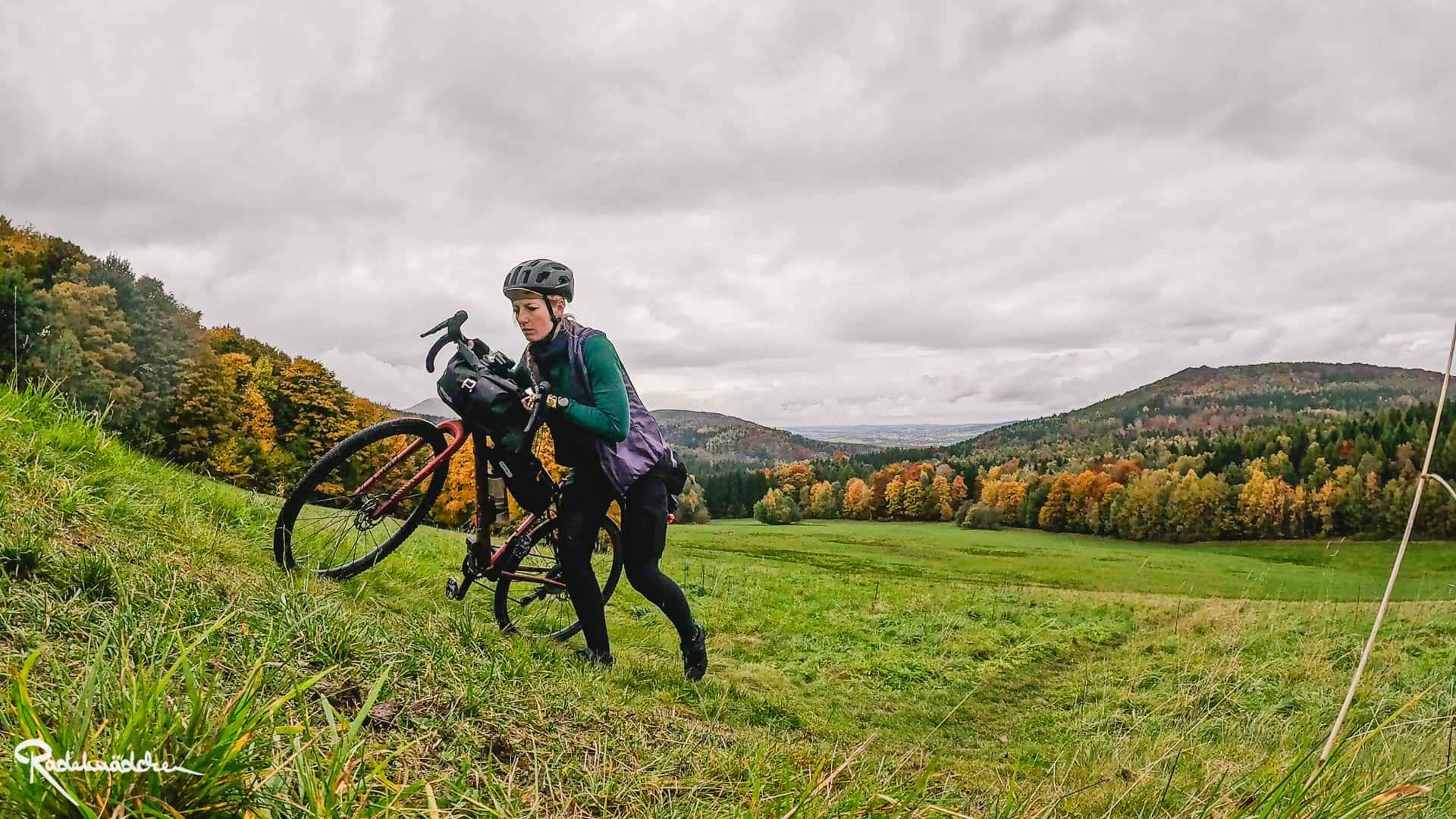 RockHead – Mit dem Gravelbike durch Sächsische Schweiz und Oberlausitz Jule schiebt Gravelbike eine Wiese hoch