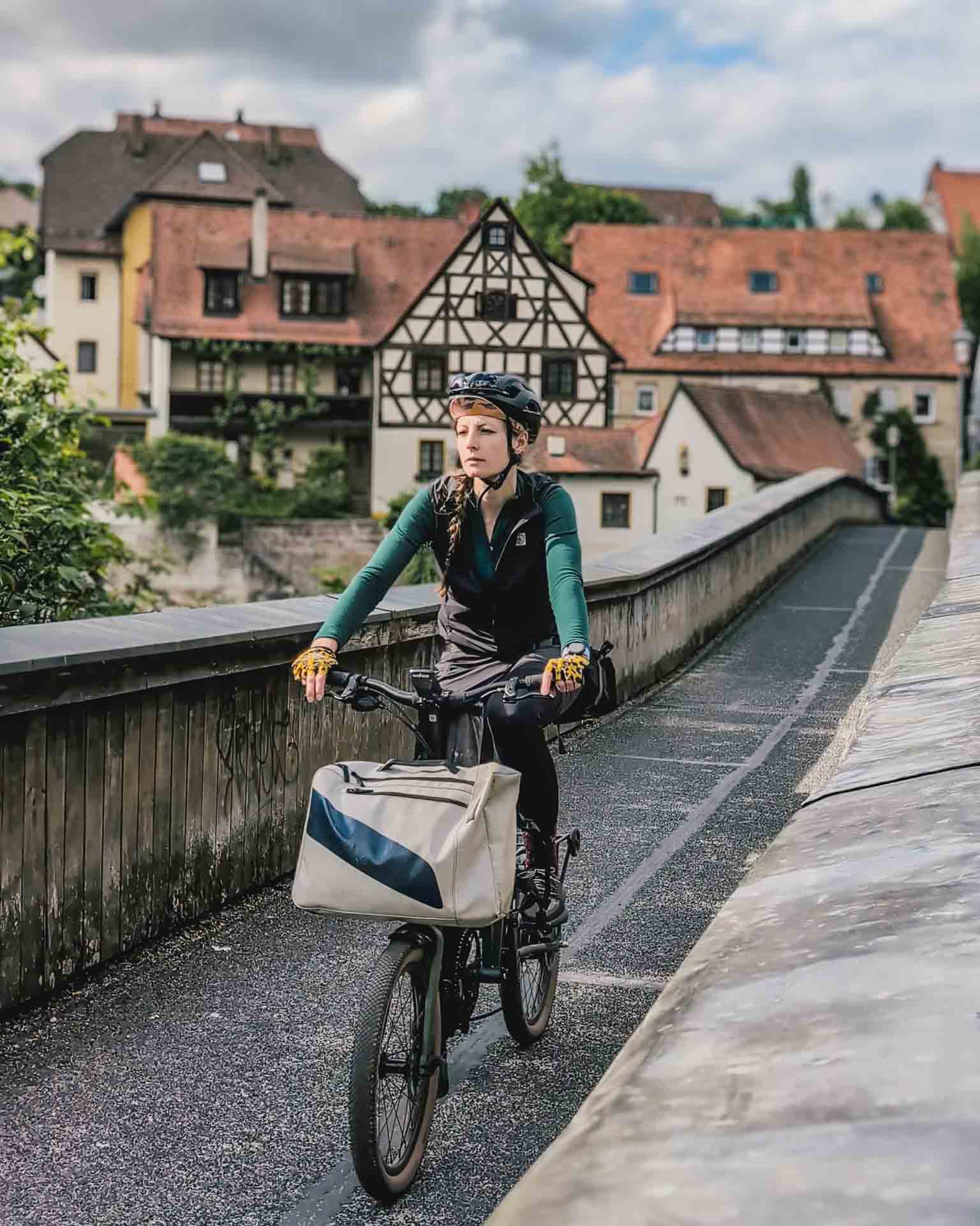 Jule auf Brompton g-Line auf einer Brücke mit Häusern im Hintergrund