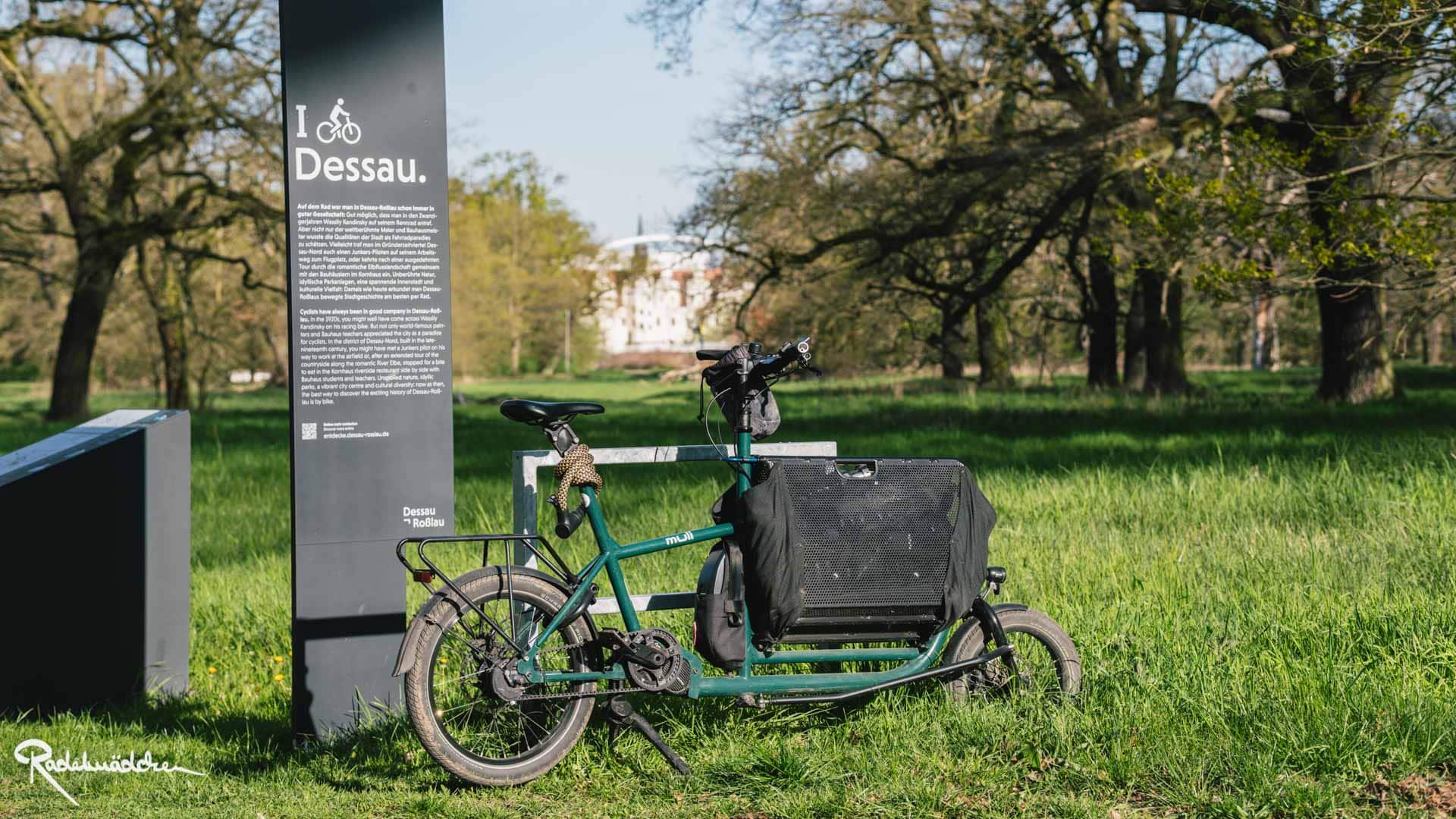 muli Cargobike im Park neben Schild